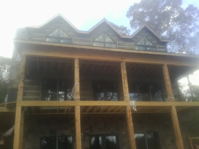 Dormers and porch framing on a large log home under construction — Roof Coating work by our crew in Logan