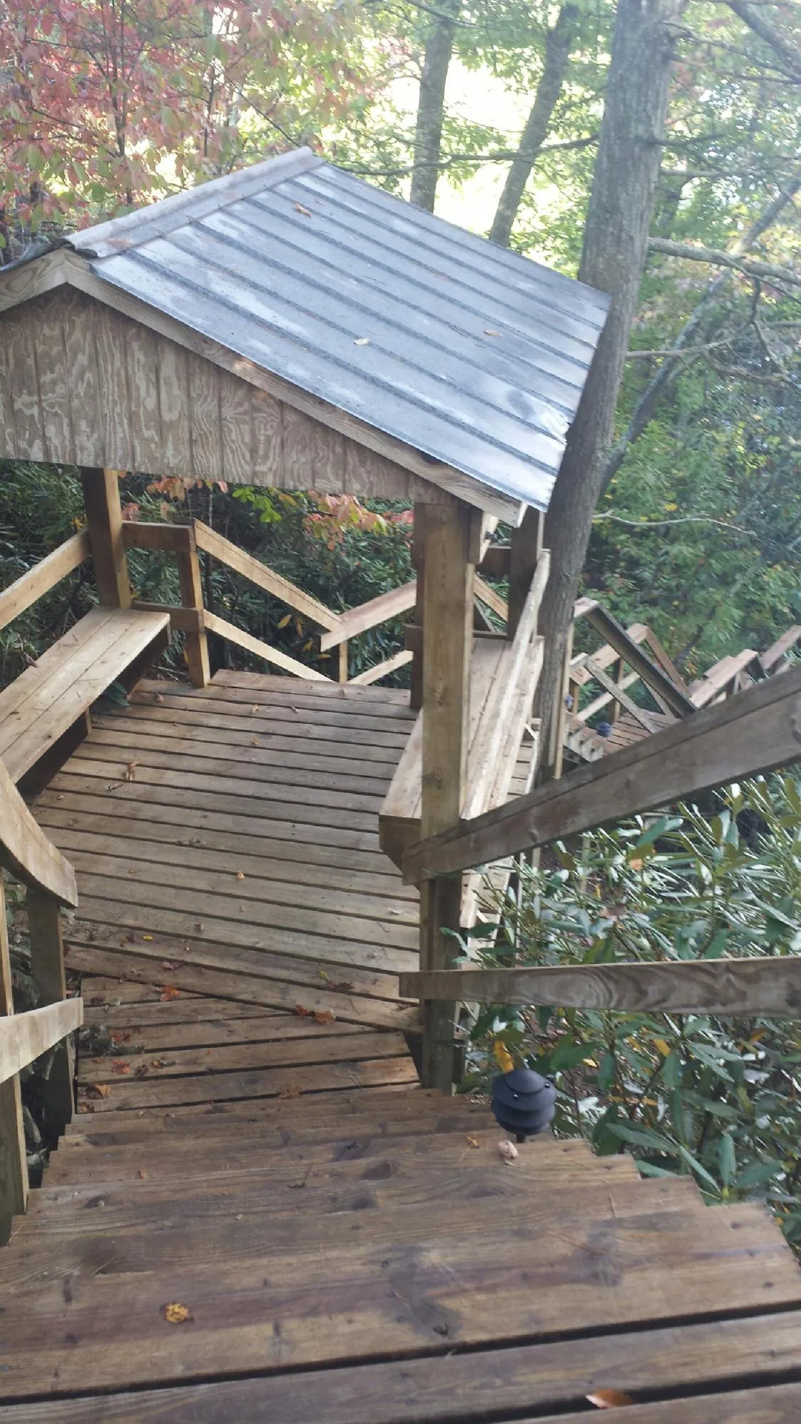 Metal roofed shelter over wooden steps on a wooded walkway — Skylight Repair & Installation work by our crew in Logan