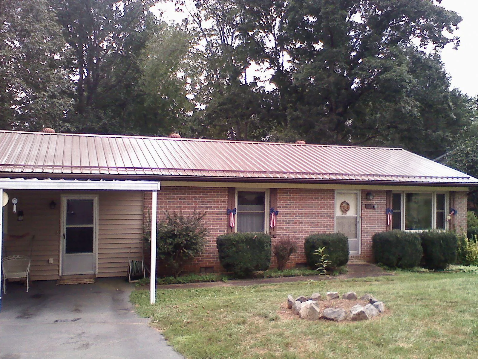 Bronze metal roof and carport on a brick ranch home — Roof Repair work by our crew in Logan